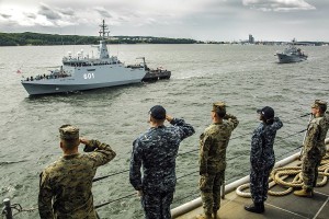 Newly commissioned Polish Navy mine hunter ORP Kormoran, built at Remontowa Shipbuilding, seen passing by USS Oak Hill. U.S. Marines assigned to the 26th Marine Expeditionary Unit (MEU) and Sailors assigned to Amphibious Ready Group 4, salute aboard the Harpers Ferry class dock landing ship USS Oak Hill (LSD 51) during pass in review as part of the celebration of the Polish Navy's 100th birthday, June 24, 2018. Oak Hill, home-ported in Virginia Beach, Virginia, and the 26th MEU are conducting naval operations in the U.S. 6th Fleet area of operations. Photo: Staff Sgt. Dengrier M. Baez / U.S. Marine Corps