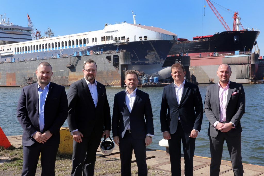 Guest from KUKE accompanied by the management of the Shipyard and the Remontowa Holding Group, with the docks in the background. Photo: Sławomir Lewandowski.